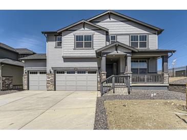 Two-story home with gray siding, stone accents, three-car garage, covered porch, and well-manicured lawn at 2968 S Poppy St, Morrison, CO 80465