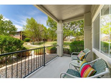 Relaxing balcony with chairs, table, and vibrant pillows overlooking the well-maintained community landscape at 2239 Calais Dr # 11F, Longmont, CO 80504