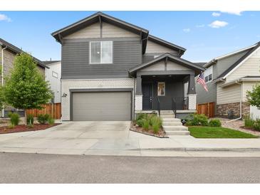 Two-story home with gray siding, brick accents, a well-kept lawn, and an attached two-car garage at 11151 W 53Rd Dr, Wheat Ridge, CO 80033