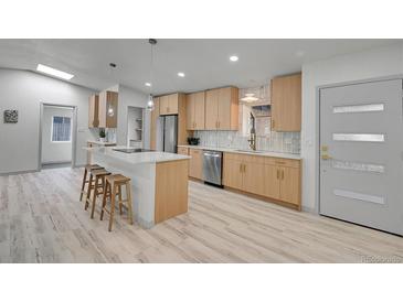 Bright kitchen with stainless steel appliances, wood cabinets, and a large island with a white countertop at 328 Quay St, Lakewood, CO 80226