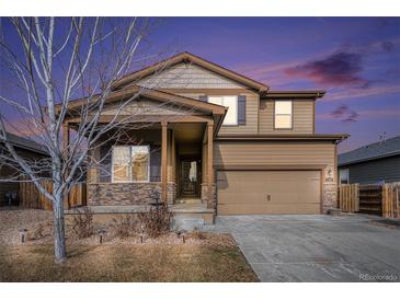 Charming two-story home featuring stone accents, neutral color palette, and an attached two-car garage, enhanced by a beautiful sunset at 1788 Taos St, Brighton, CO 80603