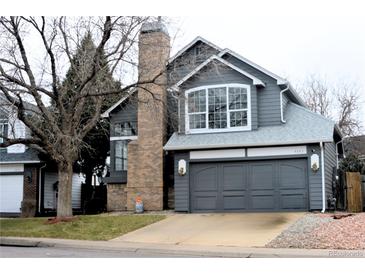 Charming two-story home features gray siding, brick chimney, and a two-car garage at 4243 Flanders St, Denver, CO 80249