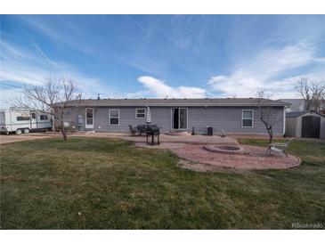 A well-maintained backyard features a patio with a fire pit, seating, and a grill ideal for outdoor entertaining at 1571 Sheridan Blvd, Lakewood, CO 80214