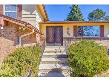 Inviting home entrance with double doors, brick accents, and landscaped bushes, offering a warm welcome at 3792 S Fenton Way, Denver, CO 80235