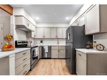 Modern kitchen with stainless steel appliances, wood floors, white countertops, and light gray cabinets at 201 Wright St # 106, Lakewood, CO 80228