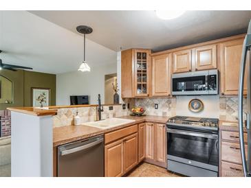 Well-lit kitchen with wood cabinets, tiled backsplash, and stainless steel appliances at 16309 Hedgeway Dr, Parker, CO 80134