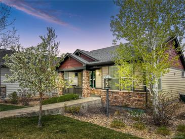 Charming single-Gathering home featuring a covered front porch, stone accents, and well-maintained landscaping at dusk at 19834 W 56Th Pl, Golden, CO 80403
