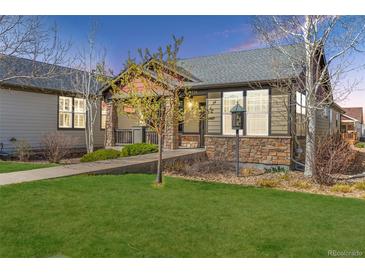 Charming home featuring a well-manicured lawn, stone accents, and a welcoming front porch at 19834 W 56Th Pl, Golden, CO 80403