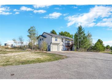 Charming two-story home features a two-car garage and a fenced yard, nestled amidst mature trees on a sunny day at 2460 Eileen Way, Parker, CO 80138