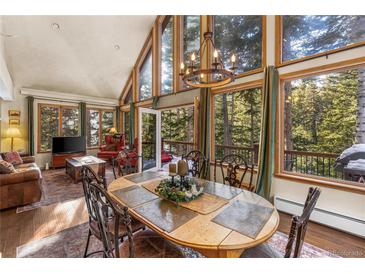 Dining room with large windows overlooking the forest and a stylish chandelier above a wooden table at 609 Brook Dr, Idaho Springs, CO 80452