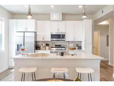 Bright kitchen with stainless steel appliances, white cabinets, and a center island with seating at 1208 Quitman St # 305, Denver, CO 80204