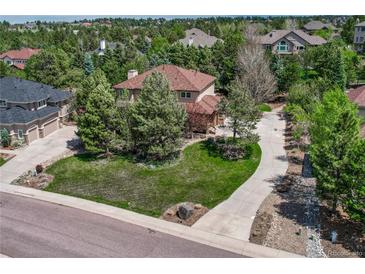 Beautiful home exterior with lush landscaping, mature trees, and a spacious front lawn at 8707 Windhaven Dr, Parker, CO 80134