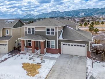 Charming two-story home with a brick-accented facade and attached two-car garage, set against a mountain backdrop at 15538 Native Willow Dr, Monument, CO 80132