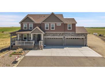 Charming two-story home features a covered porch, three-car garage, and stone accents at 49346 E County Road 6, Bennett, CO 80102