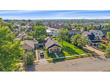 Charming home features a well-manicured lawn and inviting porch with a red door and blue chairs at 5614 Yarrow St, Arvada, CO 80002