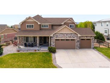 Charming two-story home featuring stone accents, a spacious driveway, and a welcoming front porch at 17378 W 78Th Dr, Arvada, CO 80007