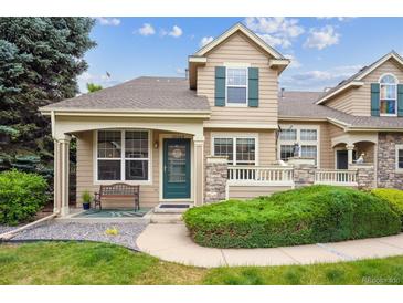 Charming home featuring a covered front porch, green door, and well-manicured landscaping at 10166 Grove Loop # D, Westminster, CO 80031