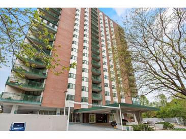 Tall brick condo building with green balconies, a covered entrance, and mature trees at 550 E 12Th Ave # 209, Denver, CO 80203