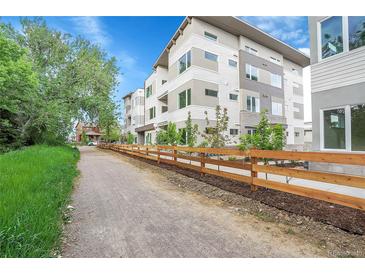 Modern condo building featuring horizontal siding, large windows, a wooden fence and landscaping at 1304 Snowberry # 103, Louisville, CO 80027