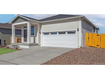 Charming single-Gathering home featuring a white garage door with windows and inviting covered porch at 9476 Yampa Ct, Commerce City, CO 80022