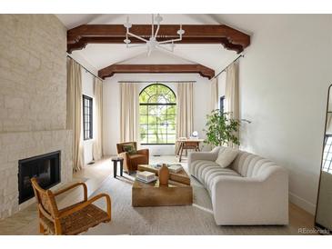 Inviting living room boasts vaulted ceilings, exposed beams, fireplace and a large arched window at 5800 E 6Th Avenue Pkwy, Denver, CO 80220