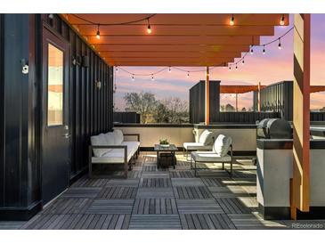Relaxing rooftop deck features stylish seating, grill, wooden flooring, and string lights for outdoor enjoyment and entertaining at 3036 Wilson Ct # 5, Denver, CO 80205