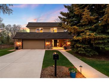 Charming two-story home featuring a well-manicured front yard and stone accents at dusk at 5020 W Quarles Dr, Littleton, CO 80128