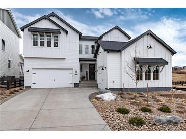 Beautiful two-story home with white siding, black trim, a two-car garage, and rock landscaping at 3898 Descent St, Castle Rock, CO 80108