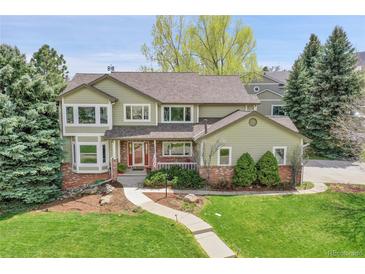 Charming two-story home with a well-maintained lawn, mature trees, and a welcoming front porch at 25 Summit Ash, Littleton, CO 80127