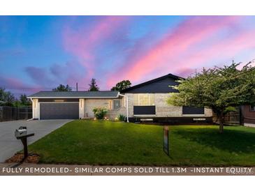 Charming single-story home featuring a well-maintained lawn, brick facade, and attached garage with a beautiful sunset backdrop at 13010 W 6Th Pl, Golden, CO 80401