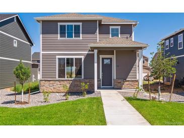 Two-story home with stone accents, gray siding, a well-manicured lawn and walkway to the front door at 28630 E 8Th St, Watkins, CO 80137