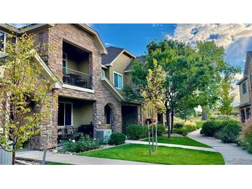 Beautiful stone townhome exterior with manicured lawn and a lovely walkway to your front door at 15362 W 66Th Ave # D, Arvada, CO 80007