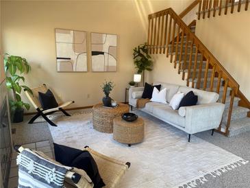 Inviting living room features neutral tones, comfortable seating, and stylish decor with staircase at 2136 S Scranton Way, Aurora, CO 80014
