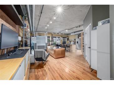 Bright, open living room features hardwood floors and modern industrial ceiling at 1499 Blake St # 4F, Denver, CO 80202