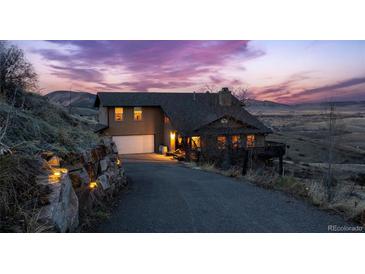 Inviting exterior of home featuring a large driveway, multi-car garage and beautiful landscaping, set against a colorful sunset at 11730 Pointe View Dr, Longmont, CO 80503