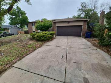 View of the house with a driveway and a garage and some landscaping at 3246 S Nucla St, Aurora, CO 80013