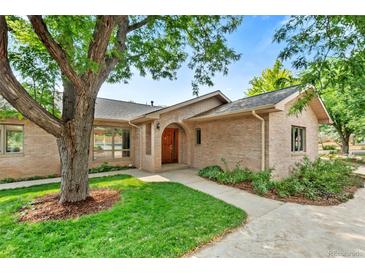 Charming brick home with an arched front door and mature landscaping, perfect for curb appeal at 6307 S Gallup St, Littleton, CO 80120