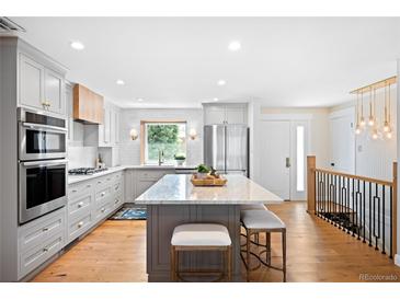 Bright, open kitchen boasts stainless appliances, large island with seating, and gorgeous cabinets at 11223 W 29Th Ave, Lakewood, CO 80215