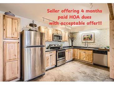 Charming kitchen featuring stainless steel appliances, natural wood cabinetry, and track lighting at 400 Zang St # 1-105, Lakewood, CO 80228