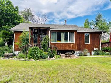 Charming single-story home featuring wood siding and a covered front porch with lush landscaping at 8211 Rocky Mountain Dr, Lakewood, CO 80214