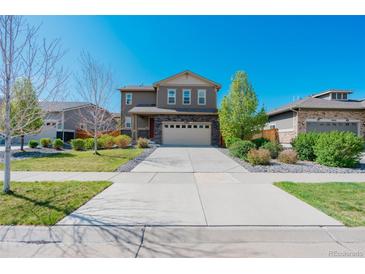 Two-story home boasts manicured lawn, stone accents, and attached two-car garage on a sunny day at 25062 E Cedar Pl, Aurora, CO 80018