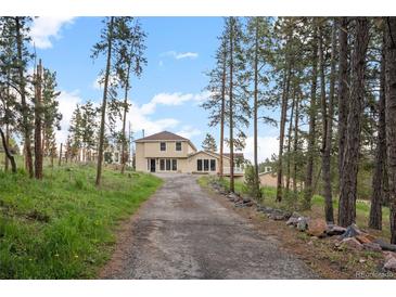 Charming two-story home with a long driveway surrounded by lush trees and natural landscaping at 27987 Pine Grove Trl, Conifer, CO 80433