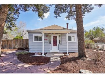 Charming cottage-style home with a red front door, stone walkway, and lush landscaping at 4290 S Cherokee St, Englewood, CO 80110