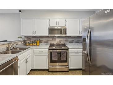 Updated kitchen featuring stainless steel appliances, tiled backsplash, and bright white cabinetry at 1818 S Quebec Way # 11-3, Denver, CO 80231