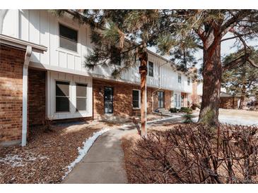 Charming townhome featuring a brick facade, white siding, and mature trees in a well-maintained community at 10330 E Jewell Ave # 67, Aurora, CO 80247