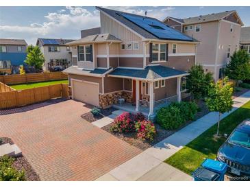 Beautiful two-story home featuring solar panels, a brick driveway, and colorful landscaping at 10071 Yampa Ct, Commerce City, CO 80022