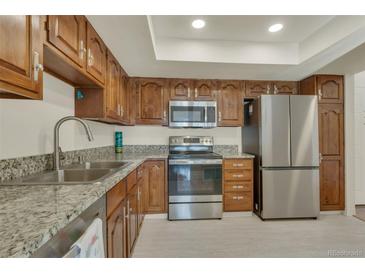 Bright kitchen featuring stainless steel appliances, granite countertops, and ample wood cabinet storage at 13901 E Marina Dr # 113, Aurora, CO 80014