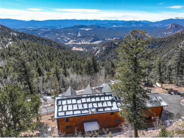 Breathtaking aerial view of a mountain home with solar panels and stunning views of the surrounding landscape at 11450 Marks Dr, Conifer, CO 80433