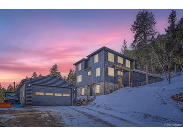 Beautiful mountain home featuring stone accents, multiple windows, and an adjacent garage under a vivid colorful sunset at 11932 Coal Creek Heights Dr, Golden, CO 80403