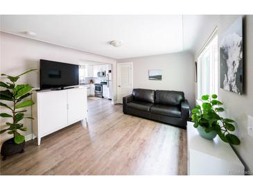 Bright living room featuring wood floors, neutral walls, and views into the adjacent kitchen at 2714 N Federal Blvd, Denver, CO 80211